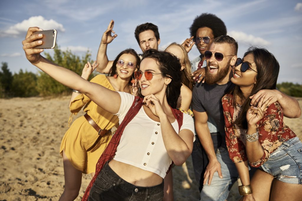 grupo amigos tomando selfie playa