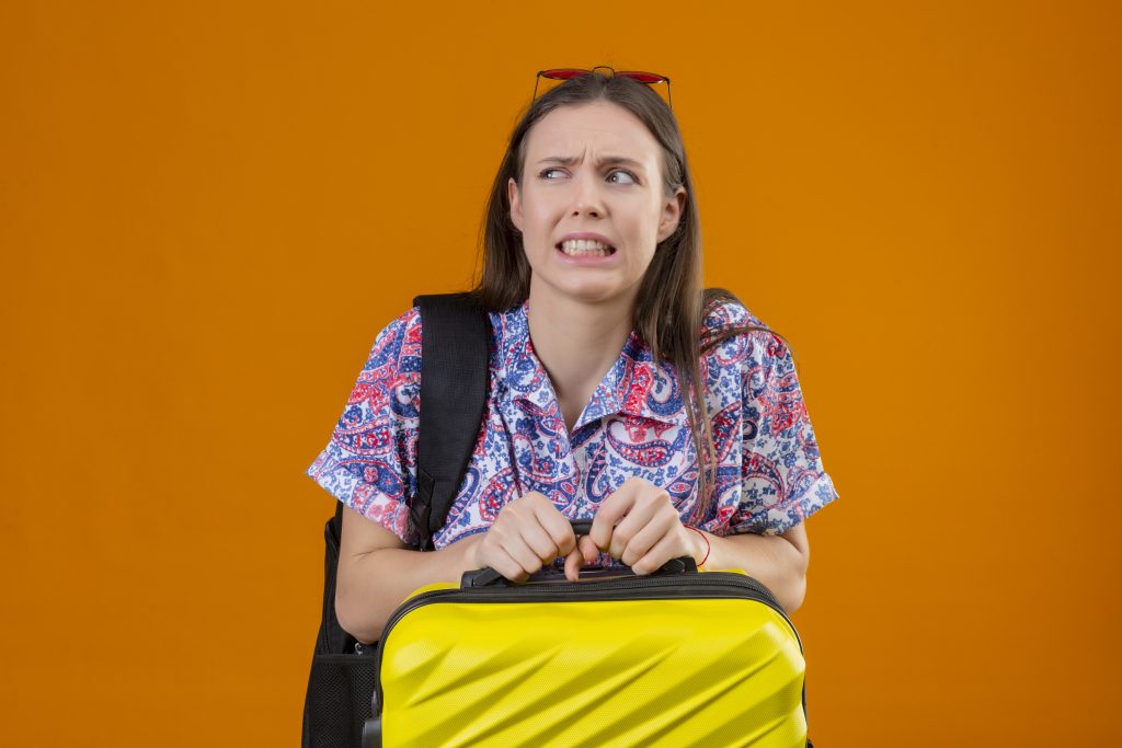 mujer joven viajera disgustada temerosa gafas sol rojas cabeza pie mochila maleta