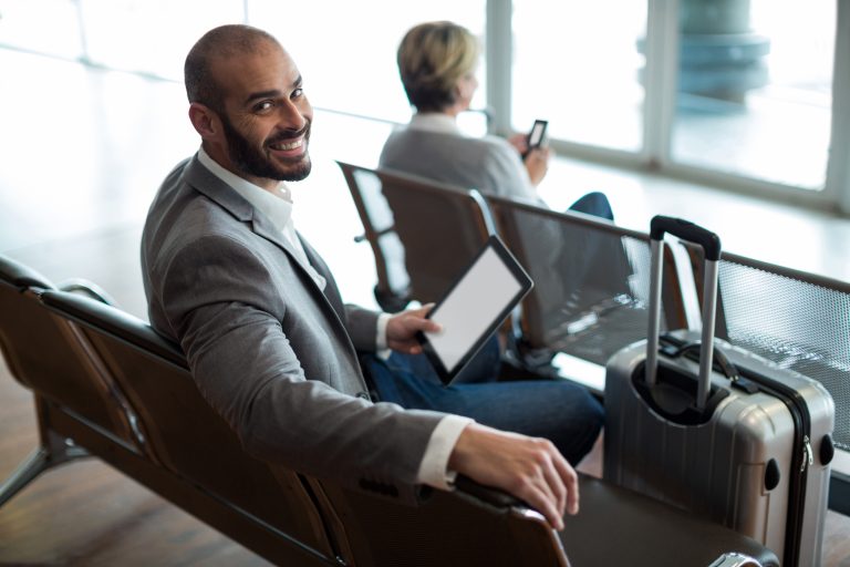 smiling businessman with digital tablet sitting waiting area